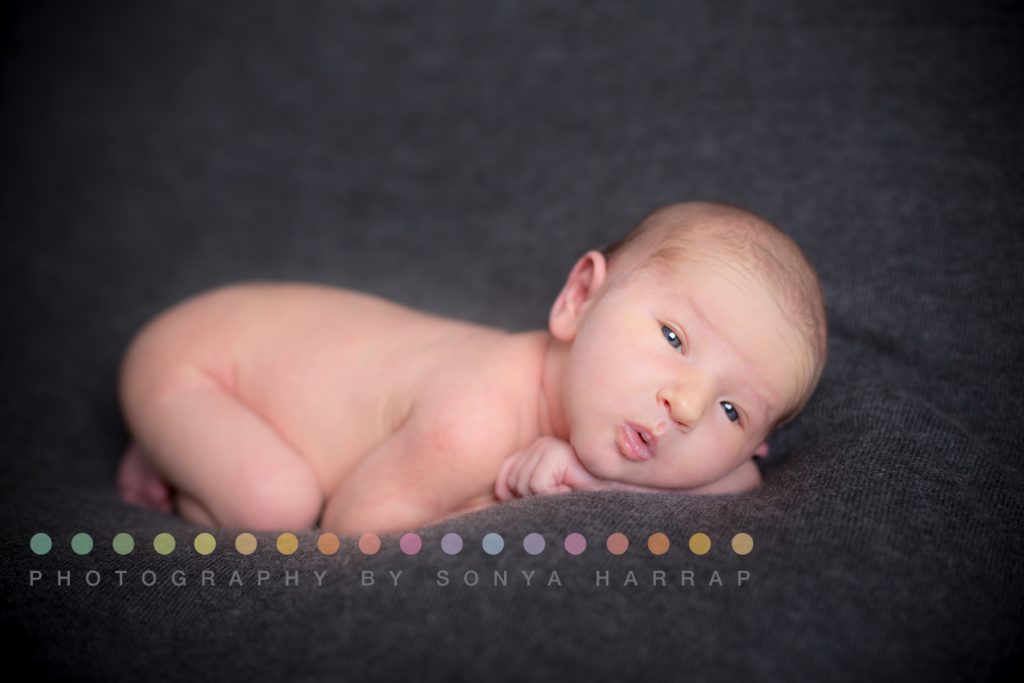 newborn baby boy photoshoot with blue eyes open and kiss lips