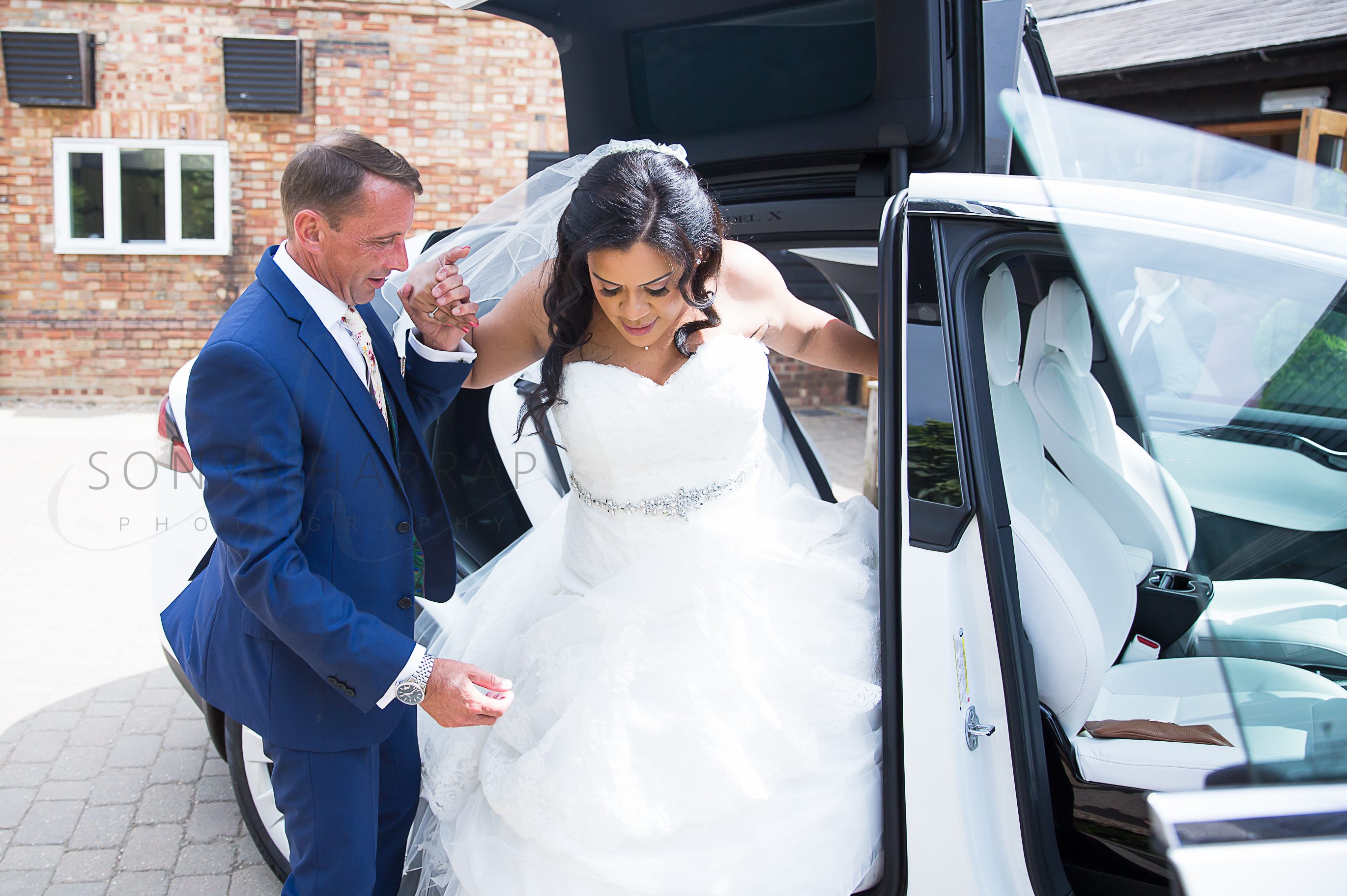 bride getting out of car before wedding ceremony Tewinbury farm hotel outdoor wedding photograph of bride and groom by Sonya Harrap photographer