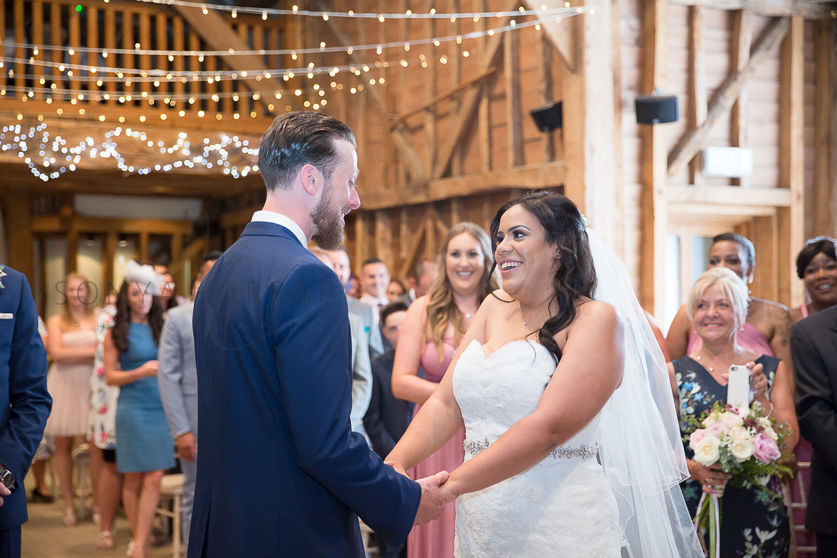 laughing and holding hands Tewinbury farm hotel outdoor wedding photograph of bride and groom by Sonya Harrap photographer