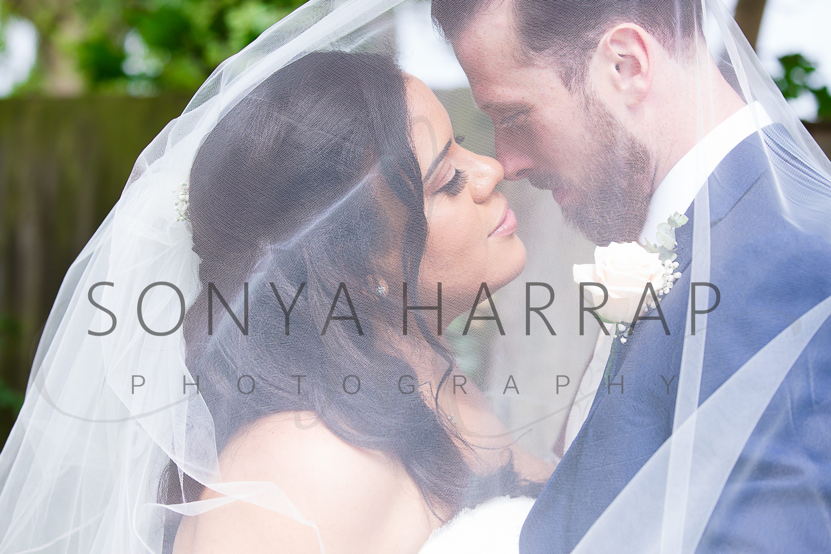 fist kiss under brides veil Tewinbury farm hotel wedding photograph of bride and groom by Sonya Harrap photographer