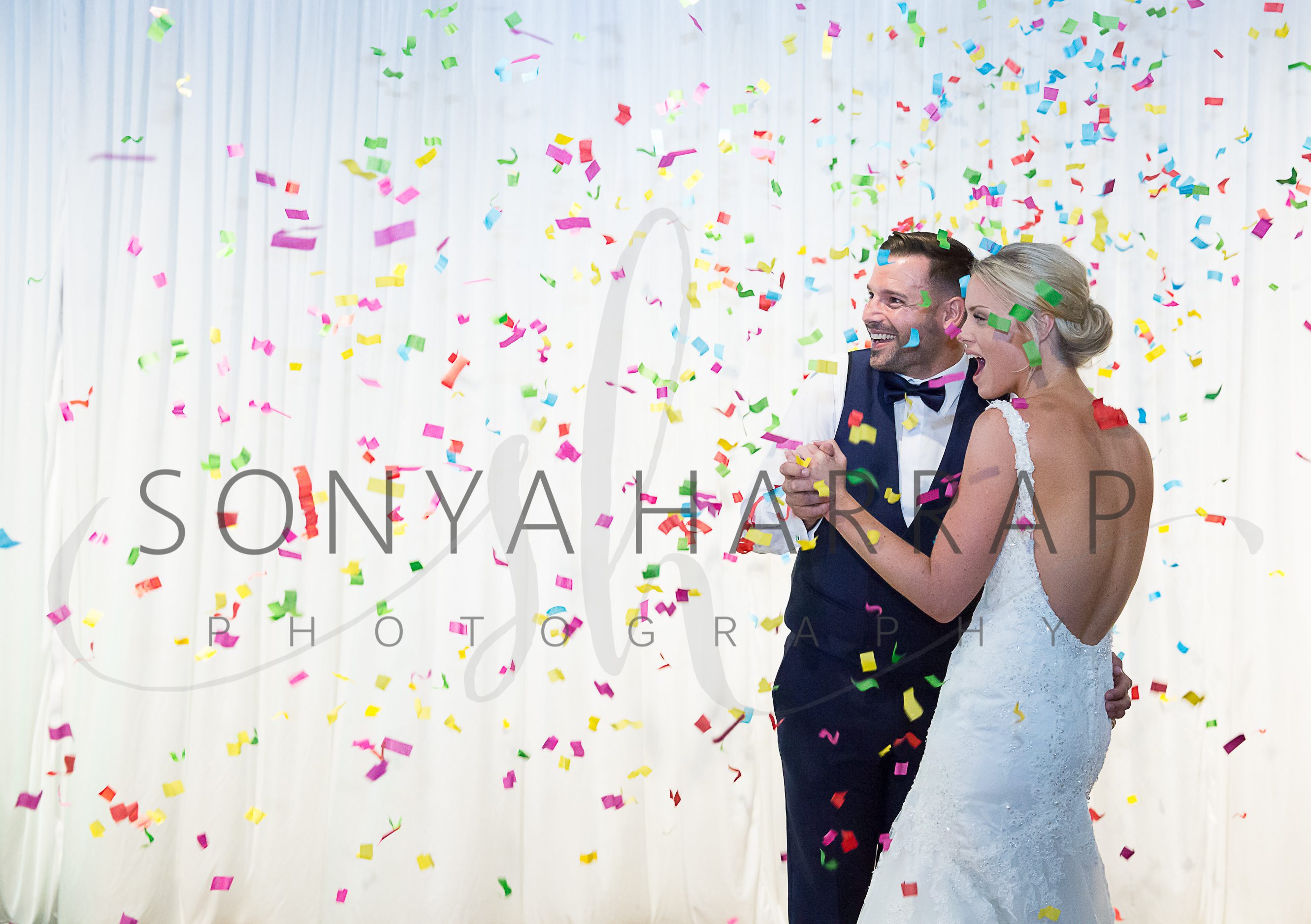 Bride and groom in confetti wedding Photography with white backdrop photography by Sonia Harrap