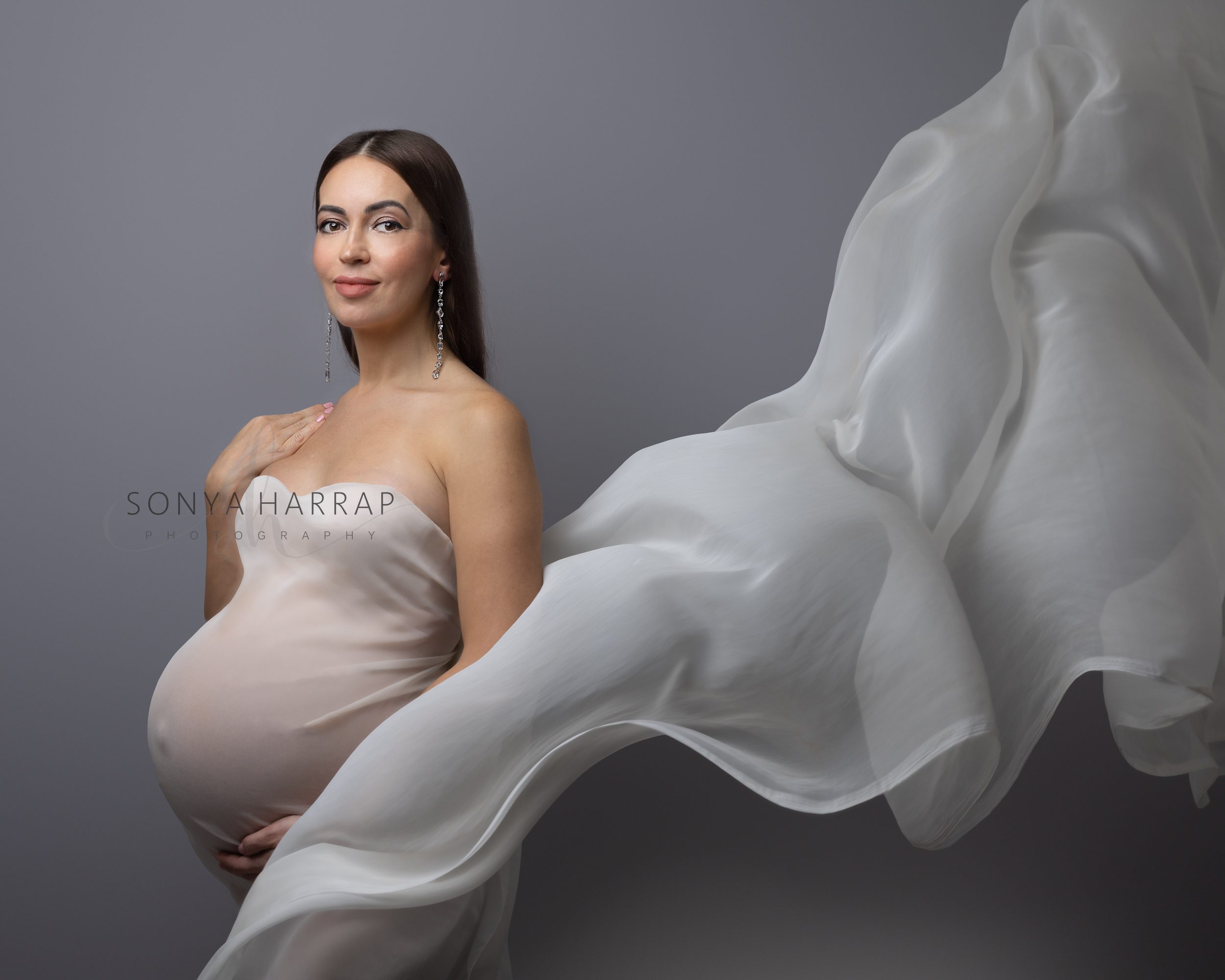 Elegant maternity photos featuring a blossoming mother in a timeless pose