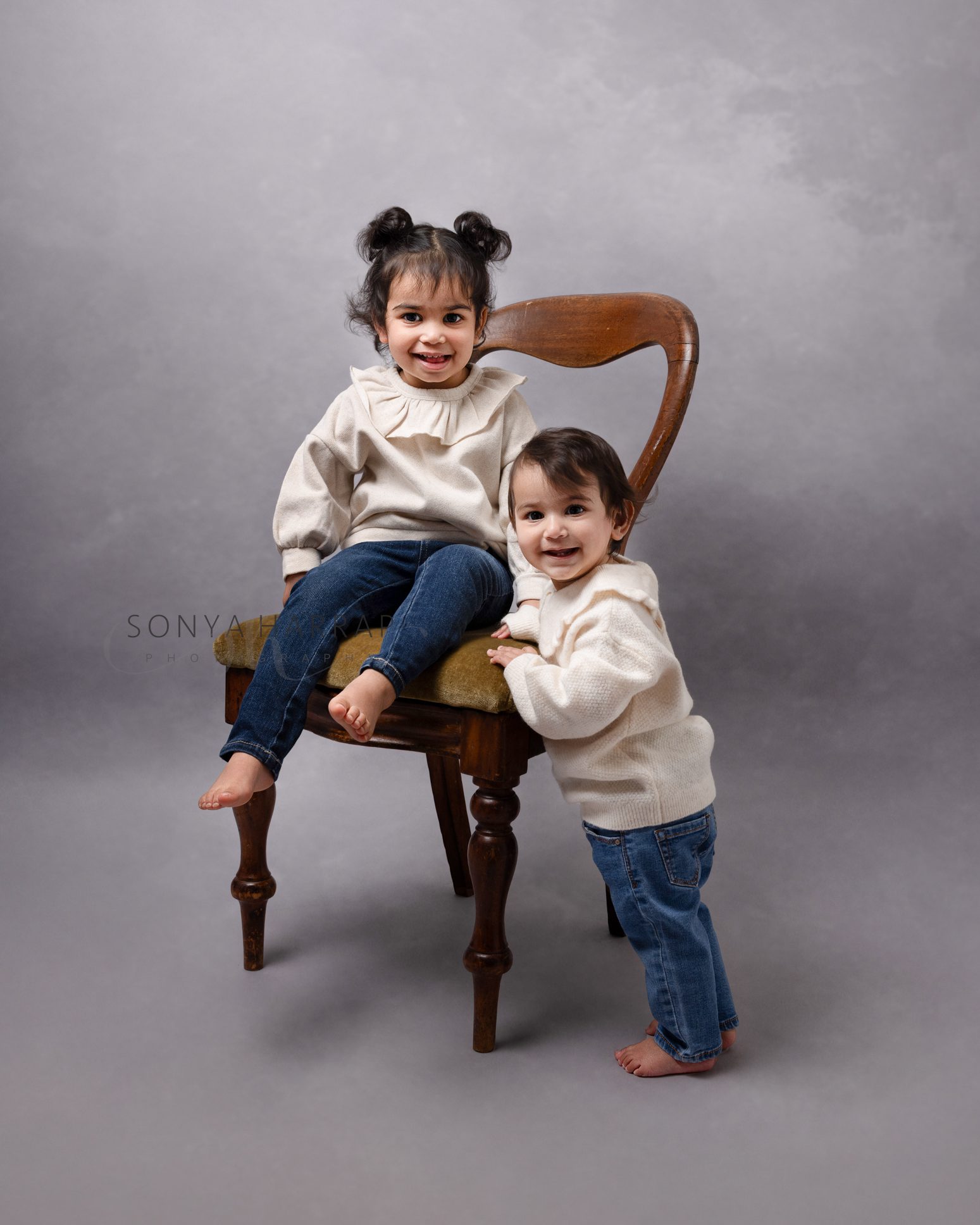 Two siblings laughing together during a relaxed children's photoshoot