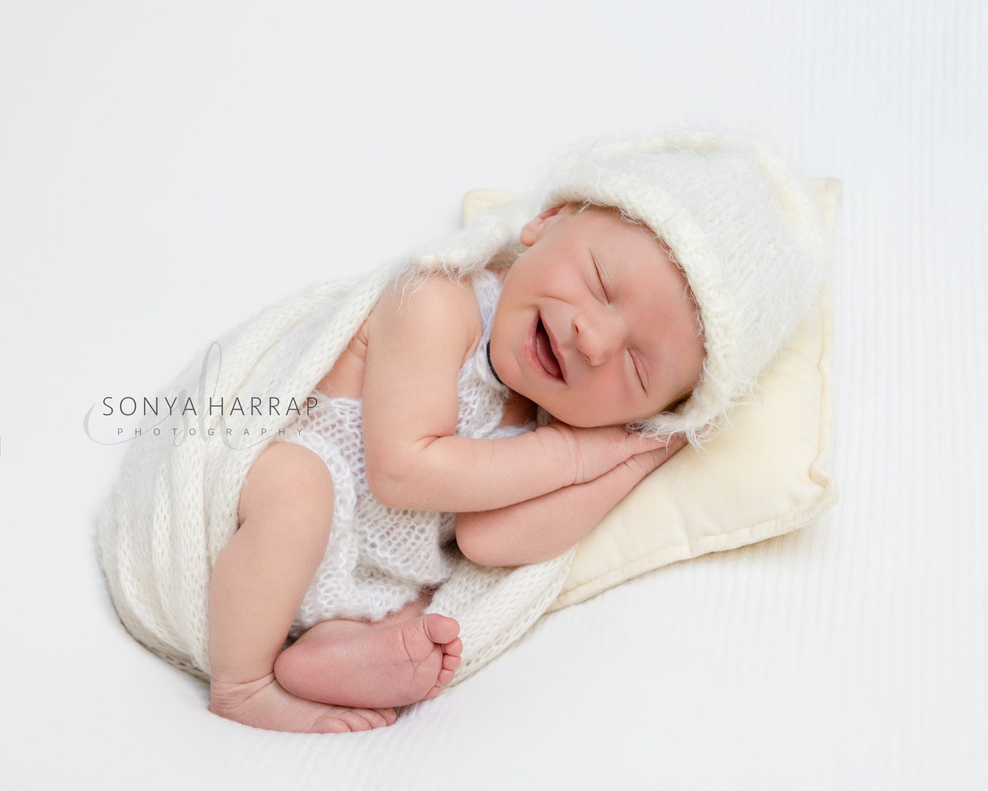 Newborn baby smiling during a relaxed baby-led photography session.