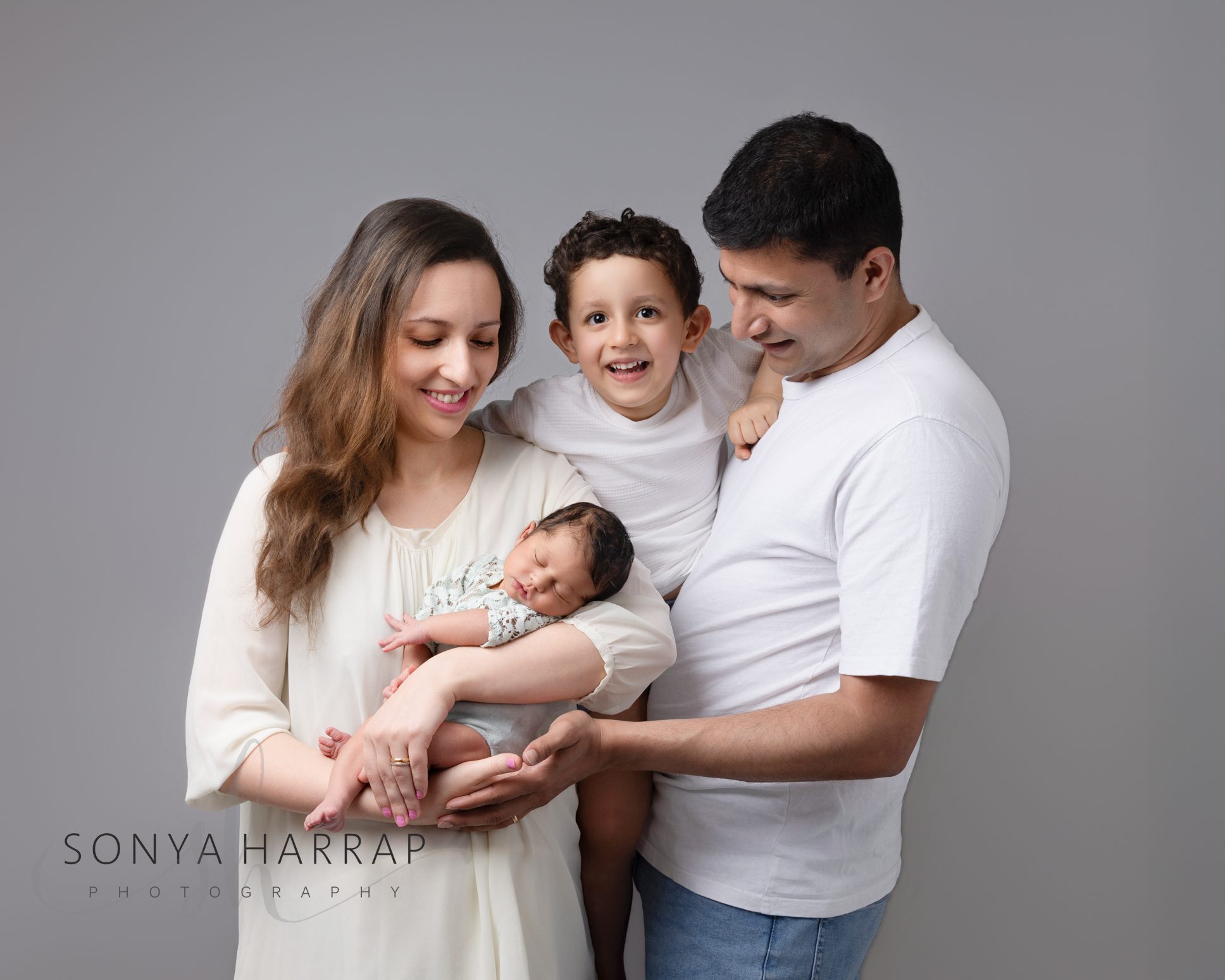 Mum and dad cuddling their newborn baby during a timeless family portrait.