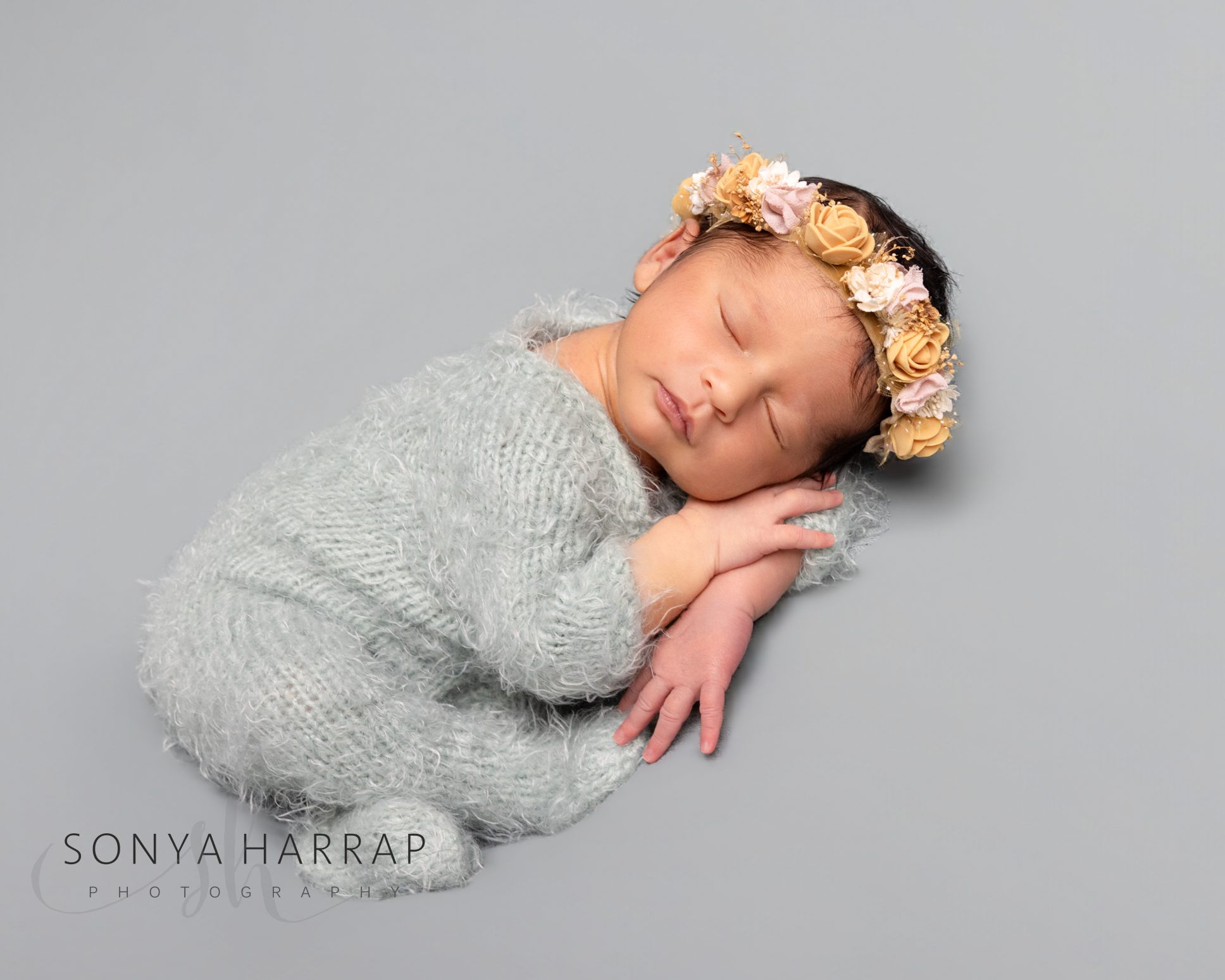 Beautiful newborn baby girl wrapped in soft fabrics during a professional photography session.