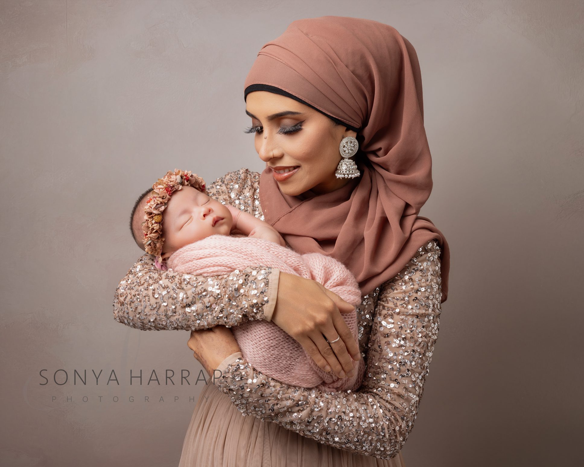 Newborn baby curled up in a natural pose in mum's arms during a professional newborn photography session.